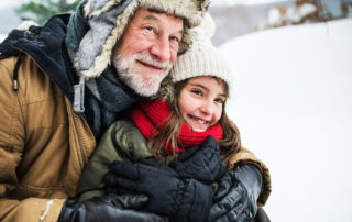 senior man with grandchild outside in the snow