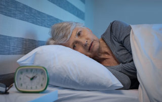 Oakleigh Macomb senior woman looking at clock in bed can't sleep