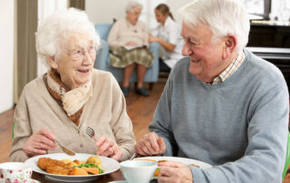 Senior couple eating at table in senior living community