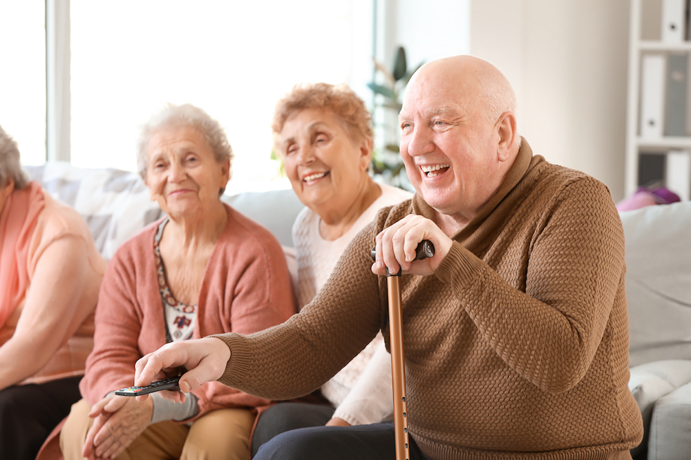 A group of senior friends watch TV and laugh together