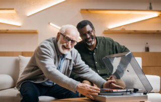 Two senior men listen to music together at assisted living