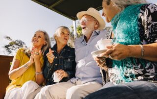 Four senior friends laugh and have tea together