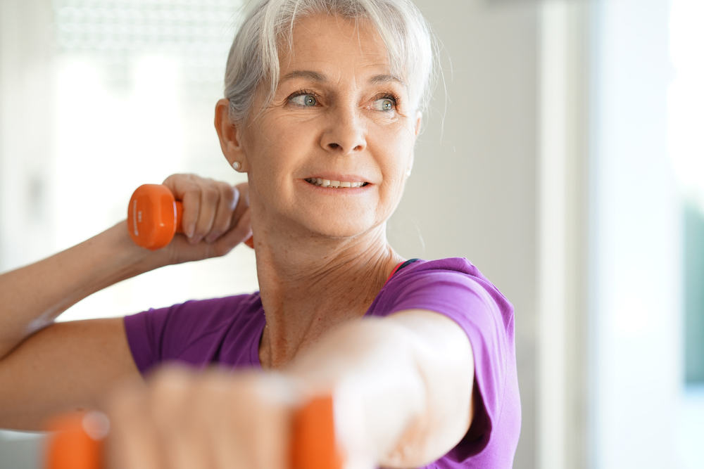 A senior woman working out with light dumb bells