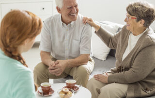 Two residents of the senior living near me sit and talk with a nurse
