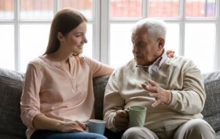 A senior man and his daughter talk and sit together