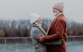 A senior couple laughing and sharing a hug while outdoors in the winter